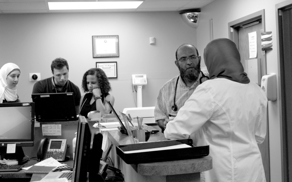 PHOTO BY CLARE HOWARD Dr. Wasim Ellahi consults with Dr. Hadeel Abdalla about computer records for a patient at Cordoba Healthcare clinic. Paulo Michelini, second from left, is explaining the computer records system to medical students at University of Illinois College of Medicine at Peoria where Michelini is a third year student. All staff at Cordoba are volunteers.