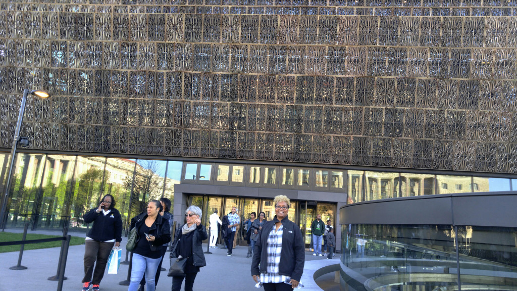 PHOTO BY BOBBI MALLORY Sherry Cannon stands outside the new Smithsonian National Museum of African American History and Culture designed by architect David Adjaye. The building is wrapped in a metal scrim based on a pattern of iron grates once made by slaves. The scrim forms an inverted step pyramid reflective of a crown from Yoruban culture in Nigeria. 
